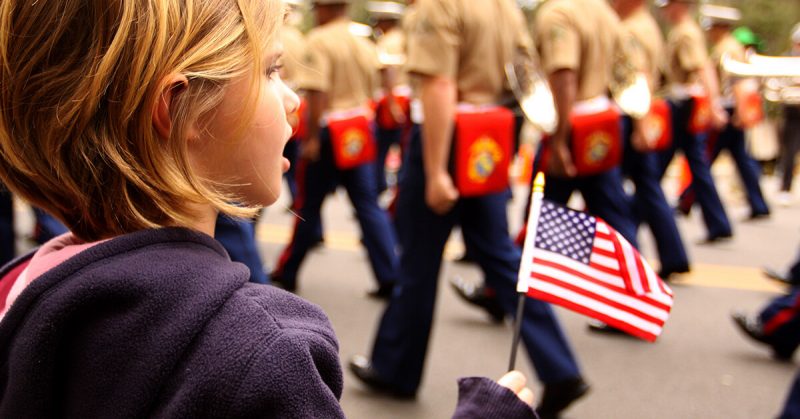 small girl holds american flag at parade
