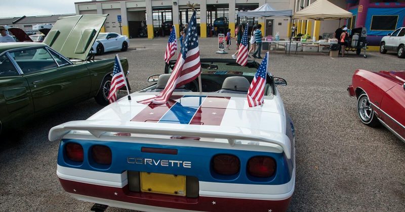 A white corvette decorated with many American flags