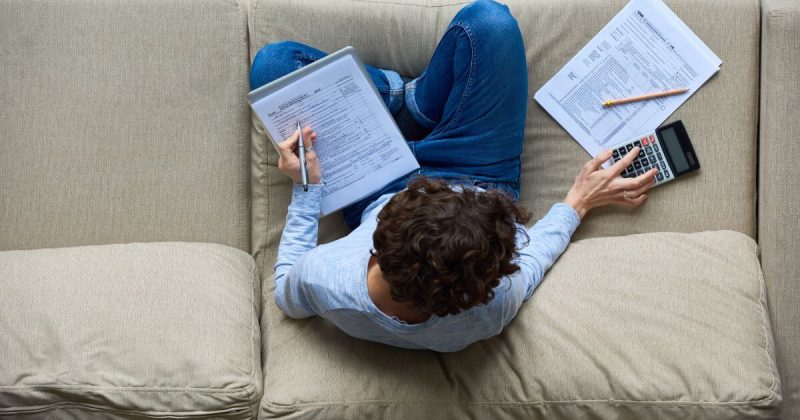 Man sitting on the couch working on his taxes
